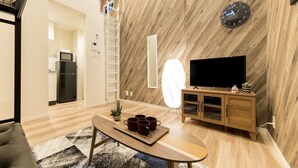 Un salon moderne avec un plancher en bois, un canapé, une table basse avec des tasses, un téléviseur et un meuble en bois.