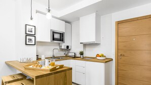Eine kleine Küche mit weißen Schränken, einer Holzauskładung, einer Mikrowelle, einem Toaster und einer Holztür.