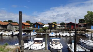 Ein Yachthafen mit mehreren angedockten Booten, Holzbauten mit roten Dächern und einem klaren Himmel.