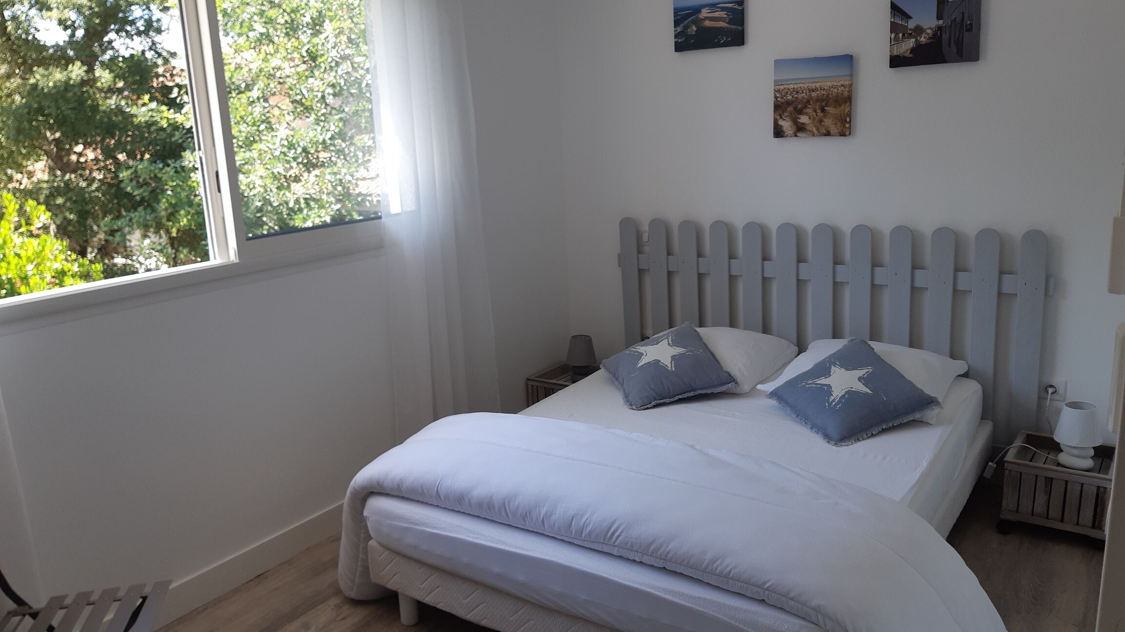 A bedroom with a bed, a nightstand, a lamp, and a window with a view of trees.