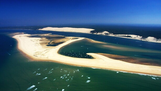 Luftaufnahme einer Küstenregion mit Sandstränden und klarem, blauem Wasser.