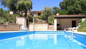 Une piscine dotée d’une terrasse carrelée, d’une échelle et de chaises longues.