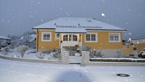 A two-story house with a snow-covered roof and a front porch. - FEWO Geisbergblick, Germany (Strullendorf)
