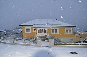 Une maison à deux étages, dont le toit est recouvert de neige et qui possède un porche à l’avant.