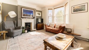 A living room with a fireplace, a grey armchair, a brown sofa, and a coffee table.