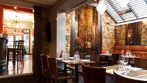 A restaurant with brick walls, wooden tables, and chairs.