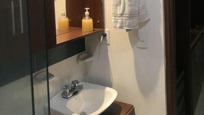 Um banheiro com uma pia de madeira, uma pia branca, um espelho e uma toalha pendurada na parede.