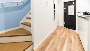A staircase with wooden steps and a blue wall, leading to a door with a sign. - Trip Pod Higashihie (Fukuoka)