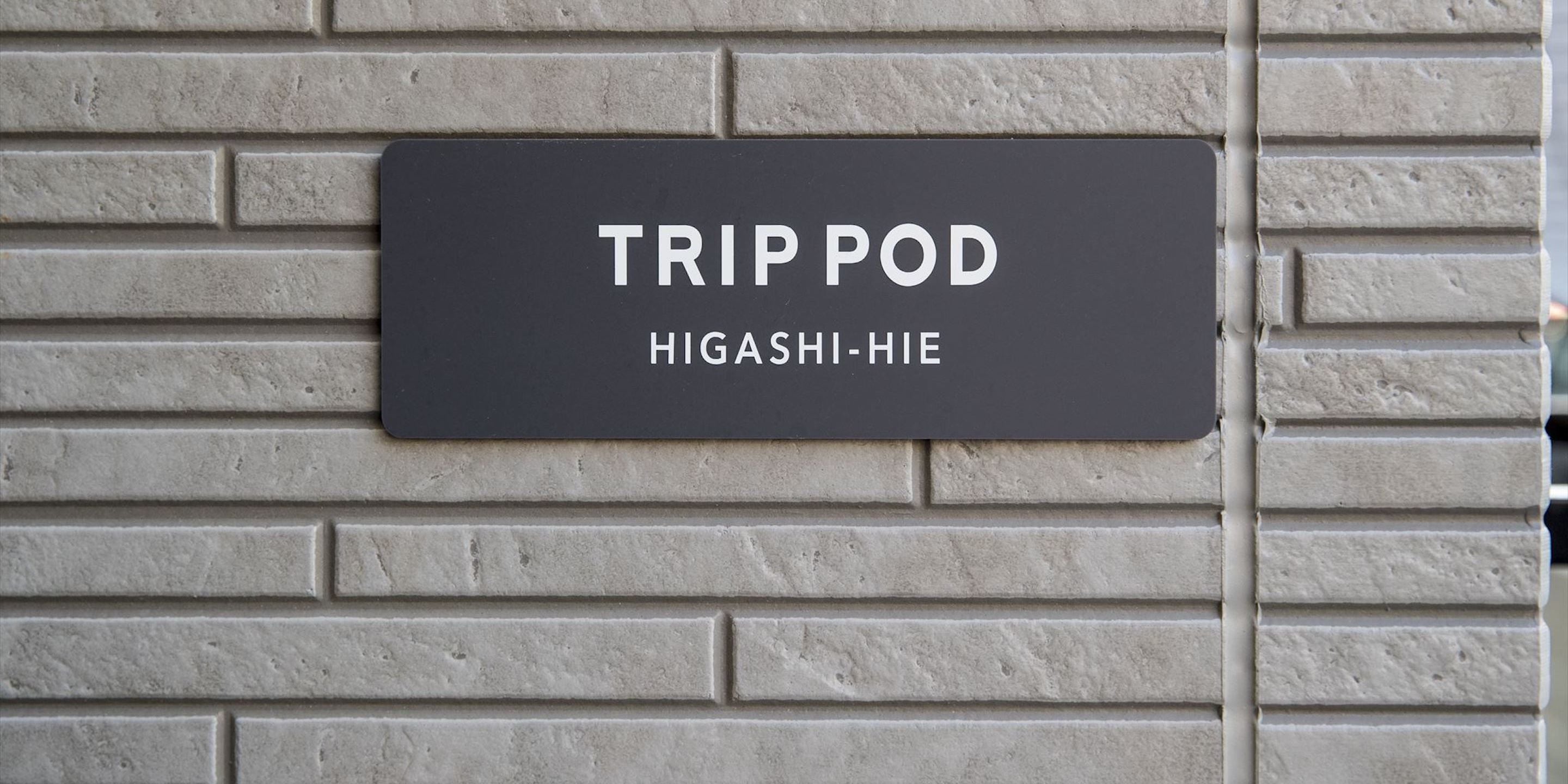 A black sign with white text on a brick wall.