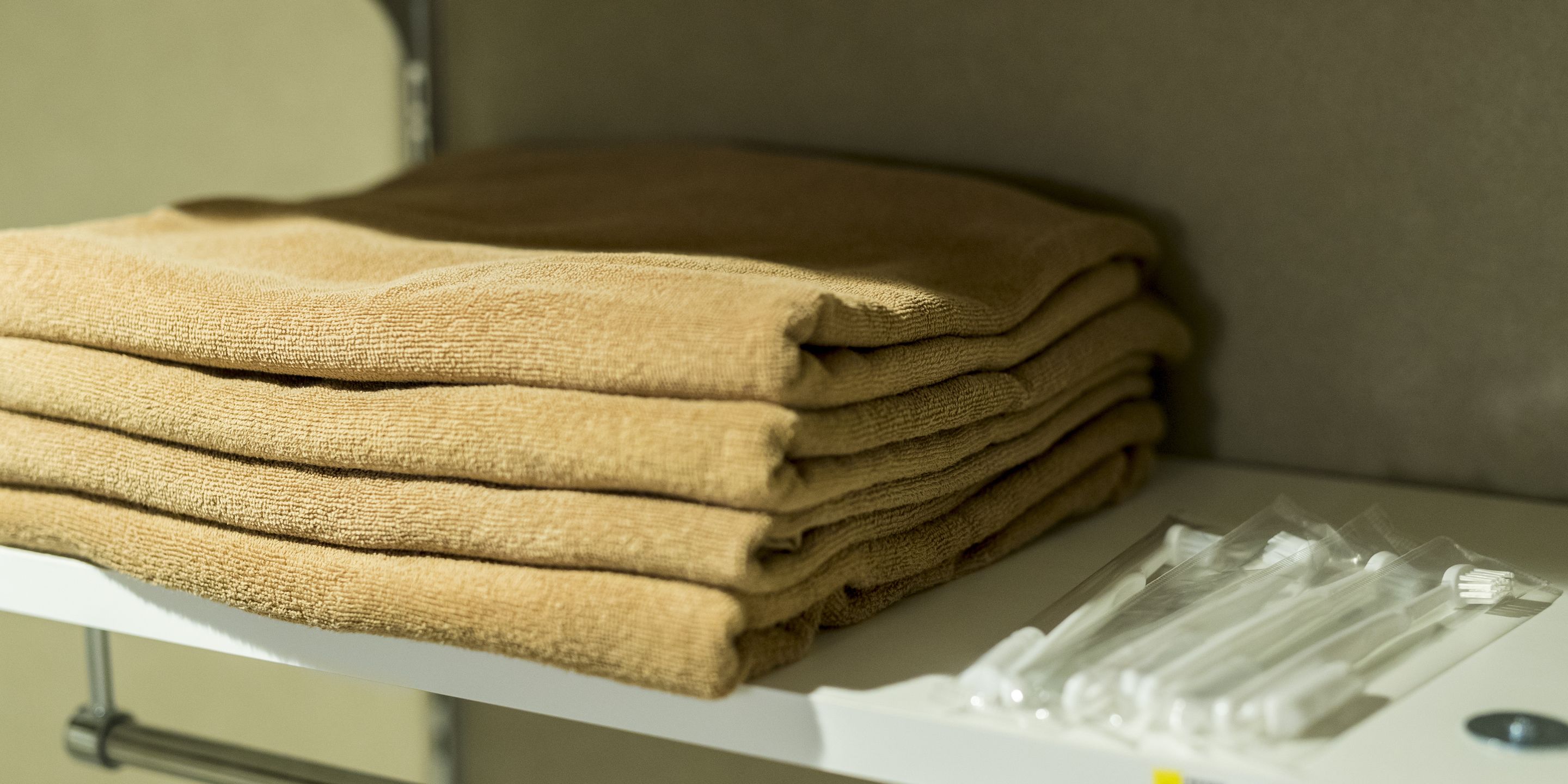 A stack of folded towels on a white shelf.