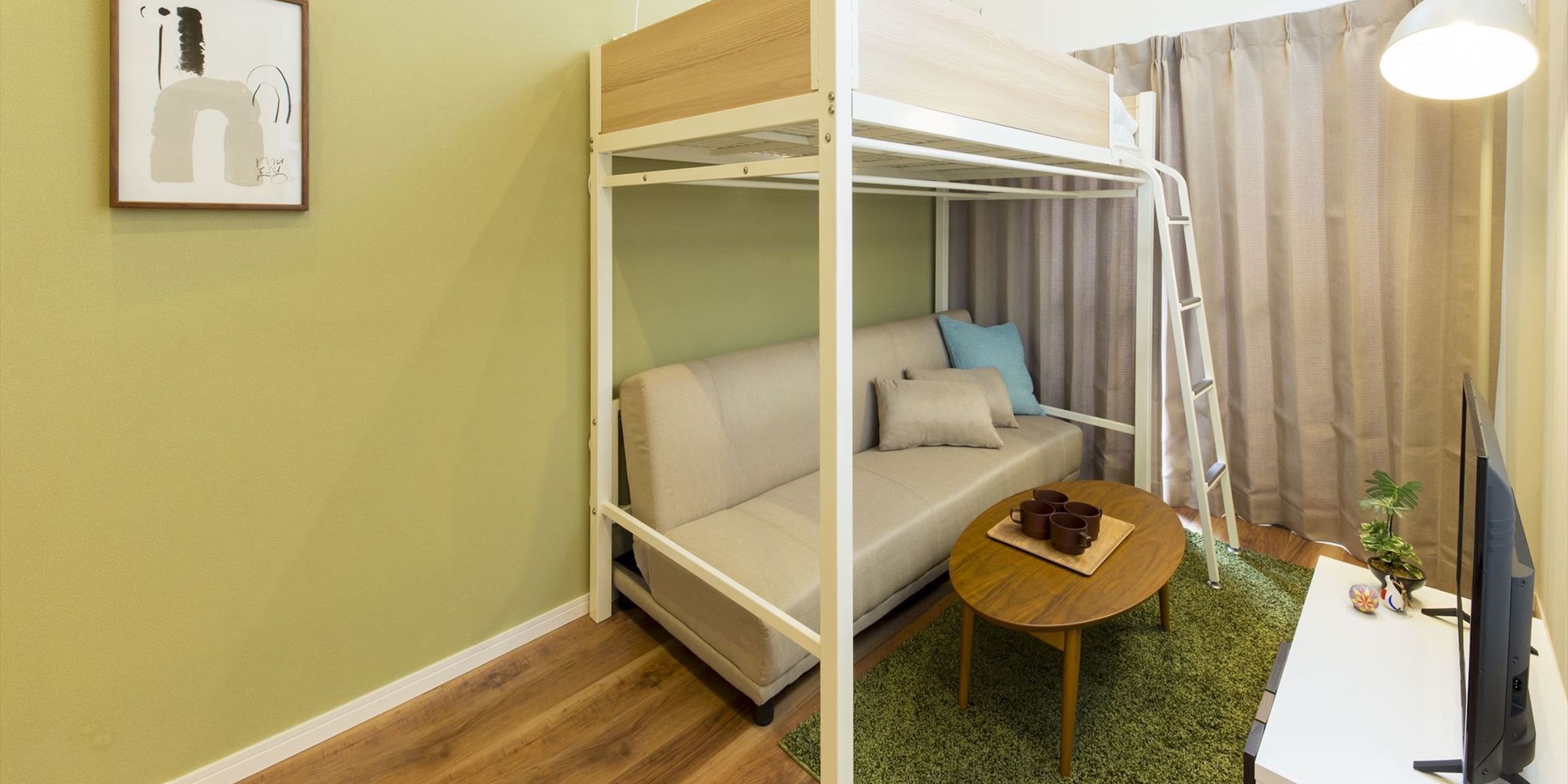 Una habitación pequeña con una cama litera, un sofá cama y una mesa de centro, además de un televisor.