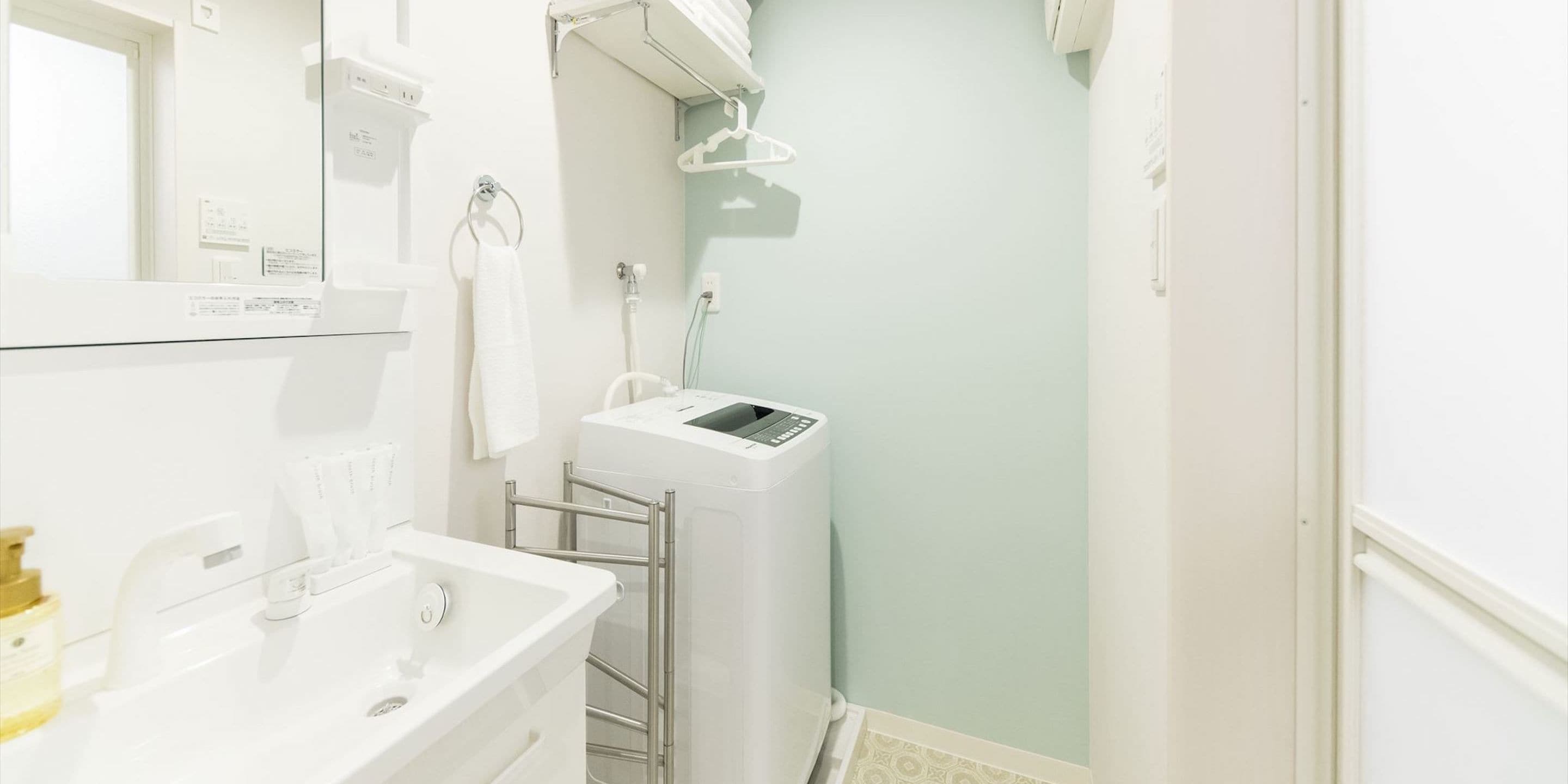 Ein modernes Badezimmer mit Waschbecken, Handtuchhalter, Dusche und Toilette, alles in Weiß.