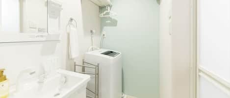 Ein modernes Badezimmer mit Waschbecken, Handtuchhalter, Dusche und Toilette, alles in Weiß.