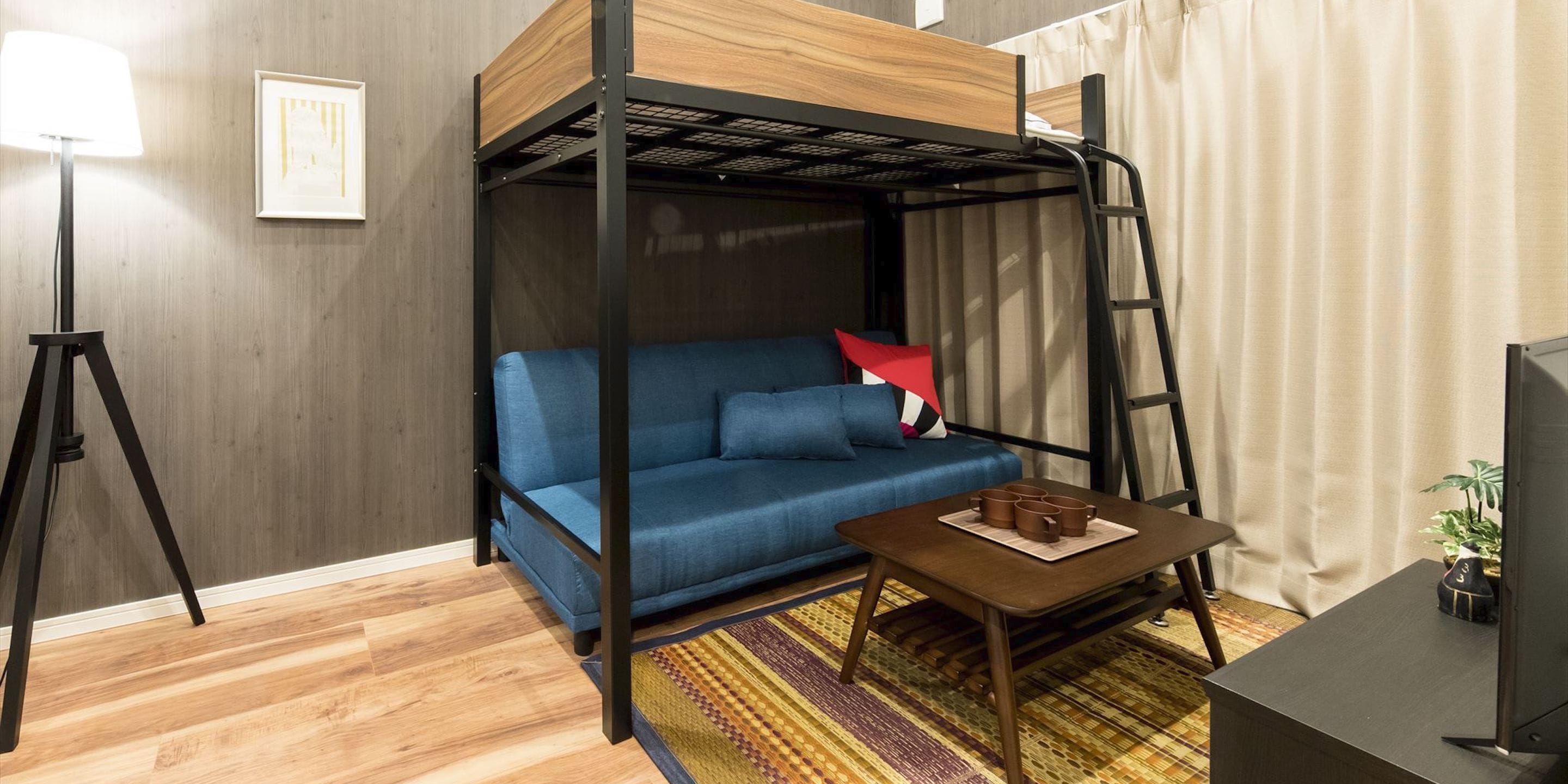 A modern room with a bunk bed, a sofa, a small table, a lamp, and a TV.