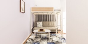 A compact room with a bunk bed, a sofa, a coffee table, and a patterned rug. - Trip Pod Higashihie (Fukuoka)