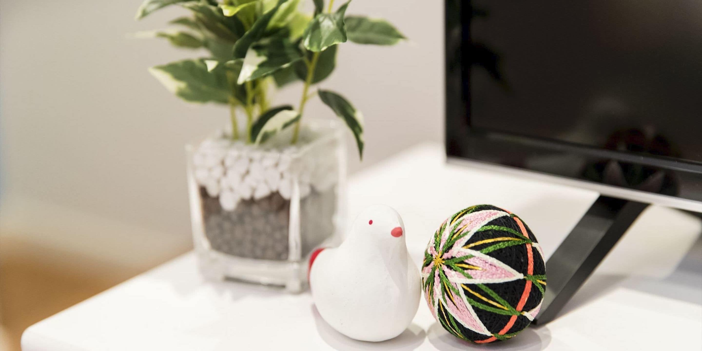A white table with a potted plant and two decorative eggs.