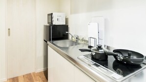 A compact kitchen with a microwave, stove, and sink. - Trip Pod Higashihie (Fukuoka)