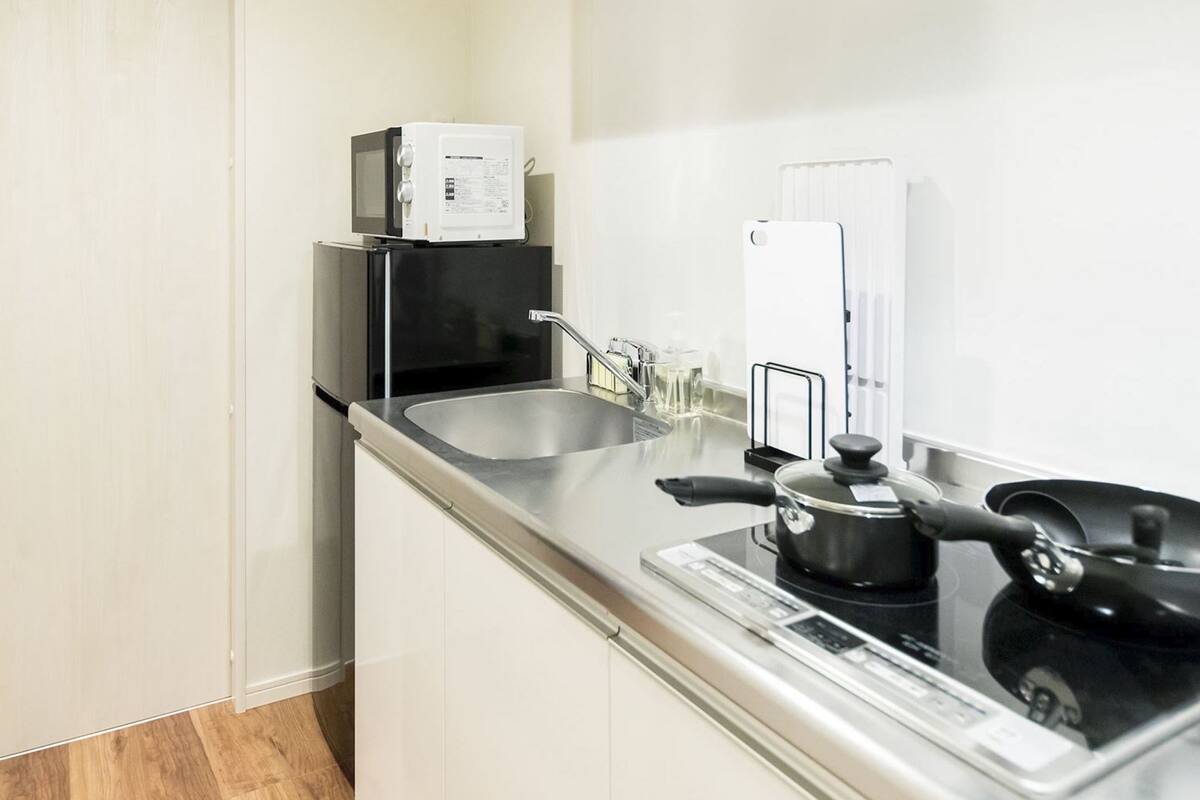 A compact kitchen with a microwave, stove, and sink.