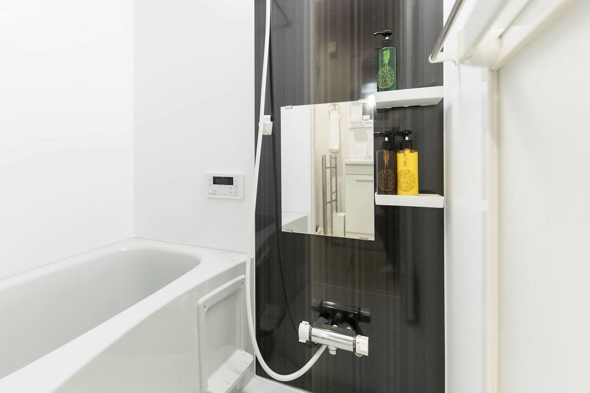 A modern bathroom with a white bathtub, a glass shower enclosure, and a mirror reflecting the room.