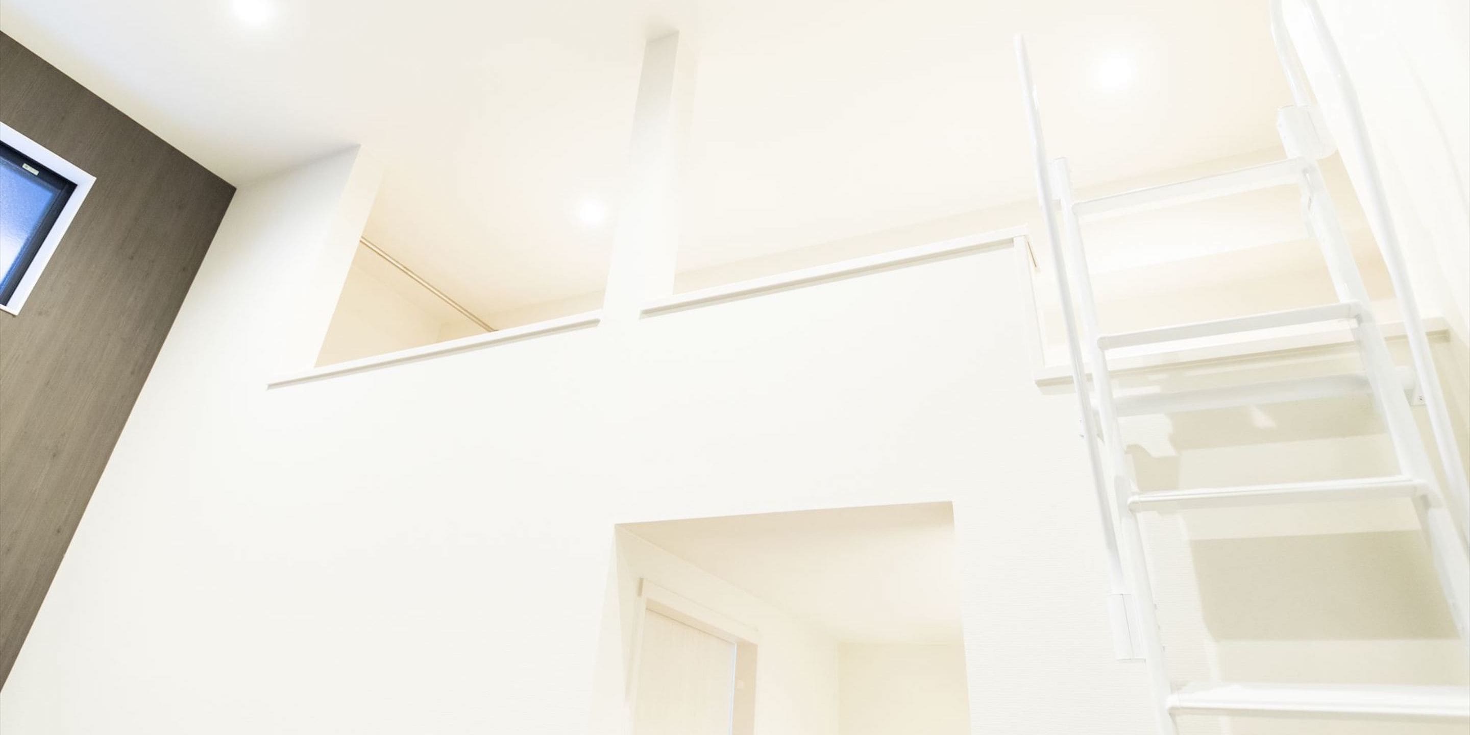 A multi-level interior with a white staircase and a window on the left.