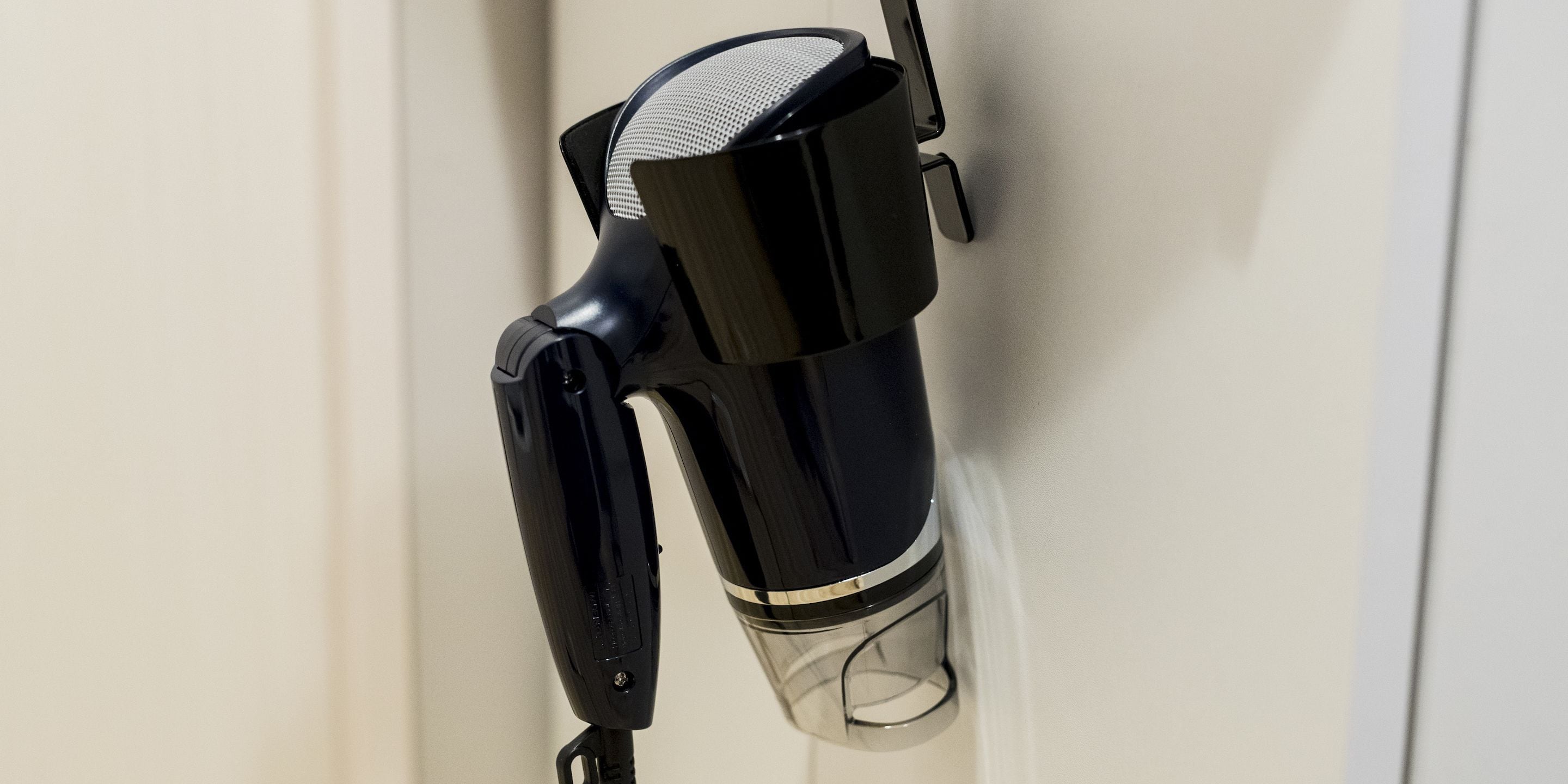 A black hairdryer mounted on a wall.