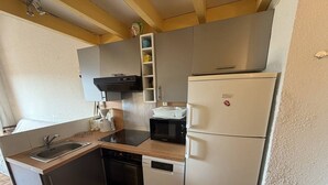 Cocina compacta equipada con fregadero, estufa, microondas y refrigerador.