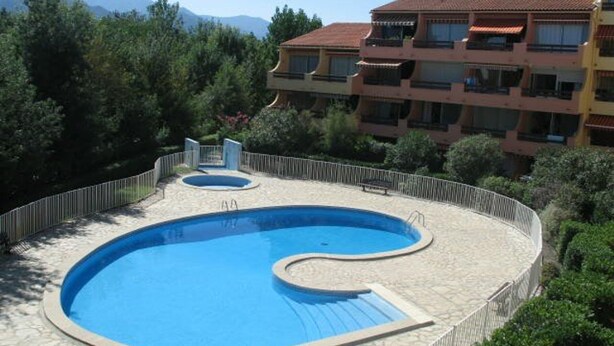 Una piscina de diseño singular, rodeada por un solárium de piedra y una valla metálica.