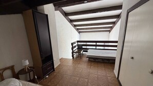 Una habitación con cama, televisor, armario y balcón con vistas.