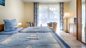 A bedroom with two beds, a nightstand, a lamp, a TV, and a wardrobe. - ***** Luisenlund Apartment, 5 bedrooms, 3 bathrooms, made-up beds, Wi-Fi, prime location, wood-burning stove, sauna (Ostseebad Prerow)