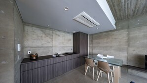 A modern kitchen with a built-in stove, a dining area with a glass table and chairs, and a recessed ceiling light. - D's GROW RESORT Infinity Pool Villa (Miyakojima)
