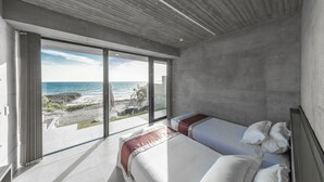 A modern bedroom with a large sliding glass door leading to a balcony overlooking a beach. - D's GROW RESORT Infinity Pool Villa (Miyakojima)