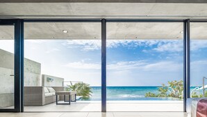 A modern room with a large sliding glass door leading to a balcony with a view of the ocean. - D's GROW RESORT Infinity Pool Villa (Miyakojima)