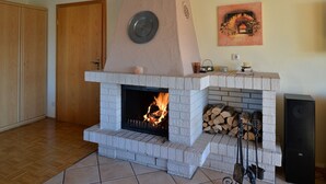 A fireplace with a stone mantle, a fire burning inside, and a speaker to the right. - Single standing top equipped house for up to 14 people. (Battenberg/Dodenau (Eder))