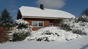 Ein Haus mit schneebedecktem Dach und einer Ziegel-Fassade.