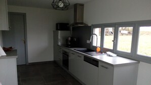 Una cocina moderna con armarios blancos, un lavamanos de acero inoxidable y una ventana con vistas a un jardín.