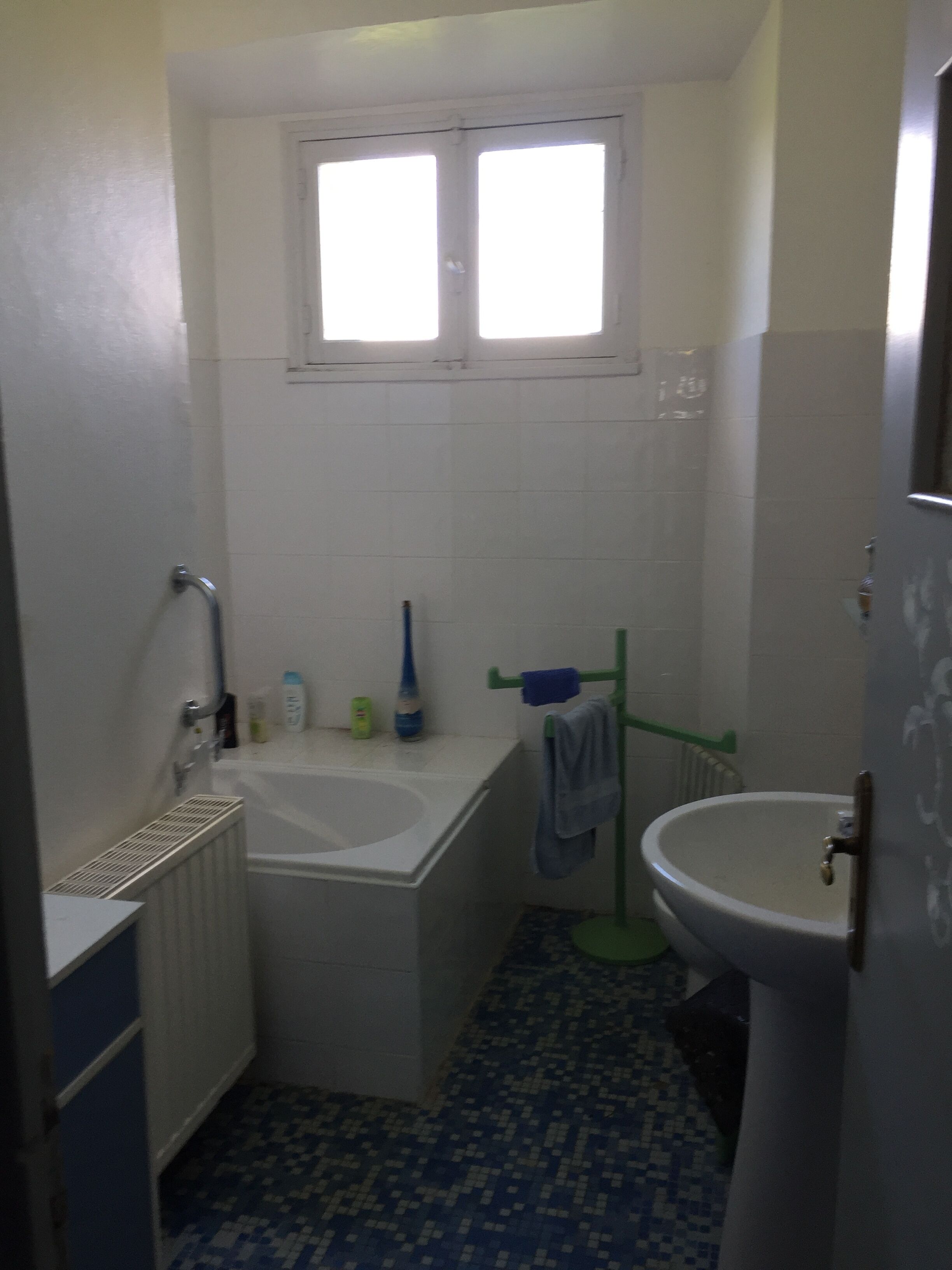Une petite salle de bain avec une baignoire, un lavabo et une fenêtre.