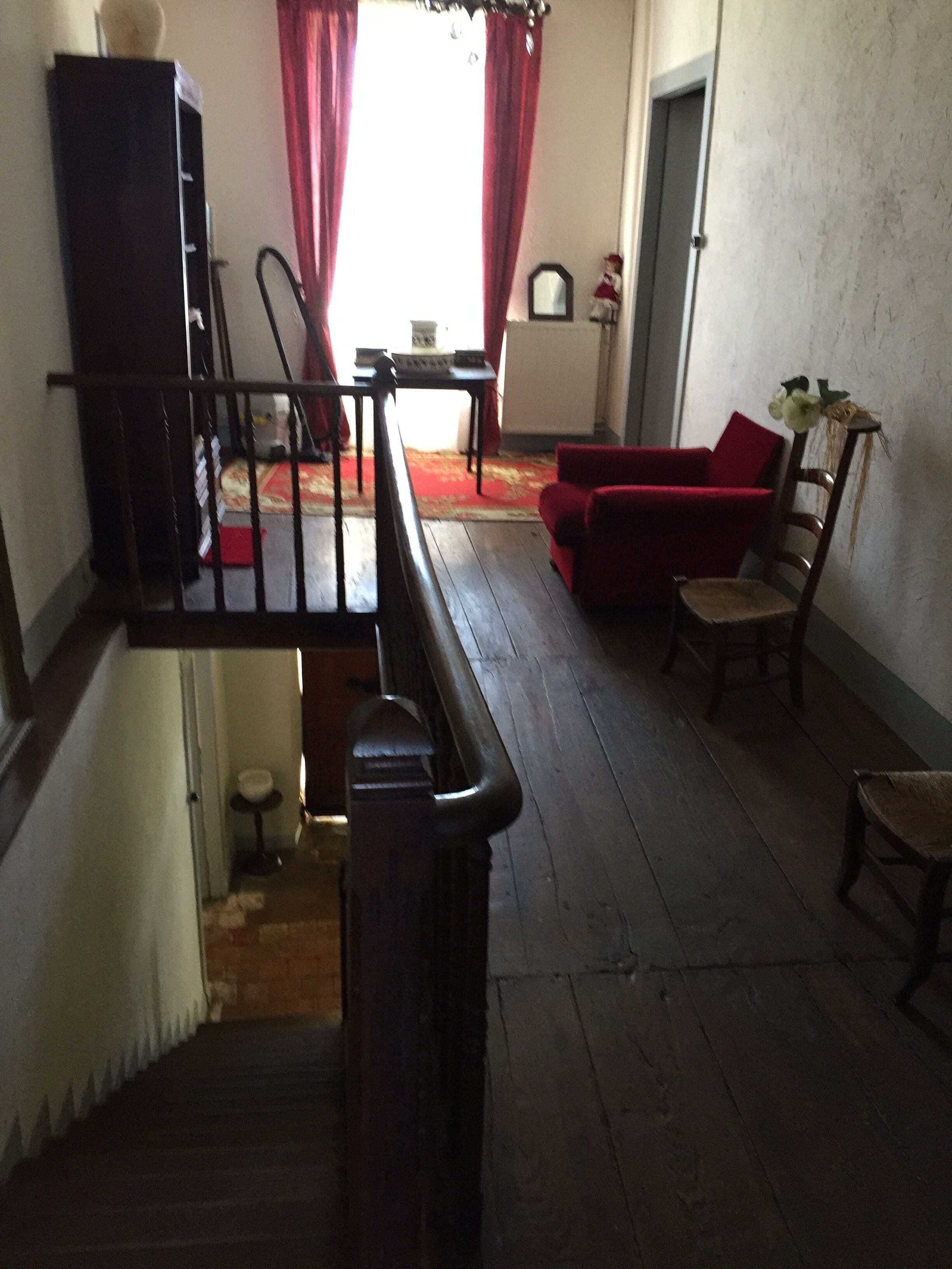 A staircase leading to a landing with a red sofa and a small table.