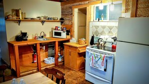 A kitchen with wooden cabinets, a microwave, a stove, and a refrigerator. - Snug and Cozy Hideaway is close to National Parks, BYU Idaho, and River Beach (St Anthony)