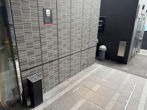 A modern building facade with a patterned wall, a trash bin, and a fire extinguisher. - APA Hotel Komagome Ekimae (Tokyo)
