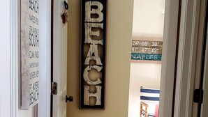 Un passadís amb un senyal de fusta que diu “PLAYA” i un cartell fixat a la paret que enumera diverses ubicacions de platges.