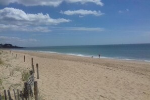 Ein Strand mit einer Holzumzäunung, einem klaren Himmel und ruhigem Meer.