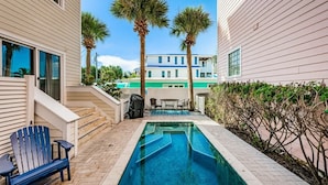 Una piscina con escalones y un patio con una silla y una mesa.