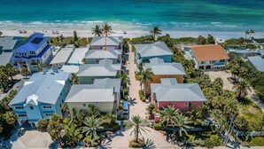 Zona residencial costera con casas, palmeras y una playa.