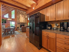 A modern kitchen with wooden cabinets, a black refrigerator, and a coffee station. - Away From Everyday - Aska Adventure Area (Blue Ridge)