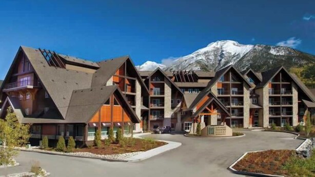 A modern hotel with a unique architectural design featuring multiple levels and a prominent mountain backdrop.