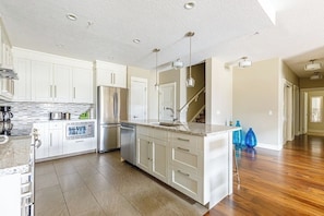 A spacious kitchen with white cabinets, a granite countertop, and a central island. - "Rocky Mountain High" - Private hot tub! (Canmore)