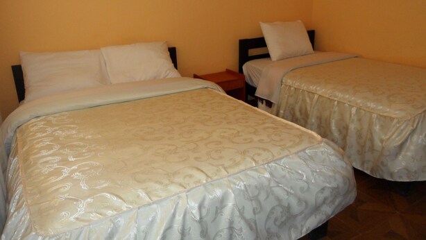 A room with two beds, each with a headboard and a pillow. - Hospedaje Imperio Inka (Cusco)