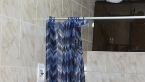 A bathroom with a toilet, a shower curtain, and tiled walls. - Hospedaje Imperio Inka (Cusco)