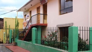 A building with a green and yellow facade, a metal fence, and potted cacti. - Hospedaje Imperio Inka (Cusco)