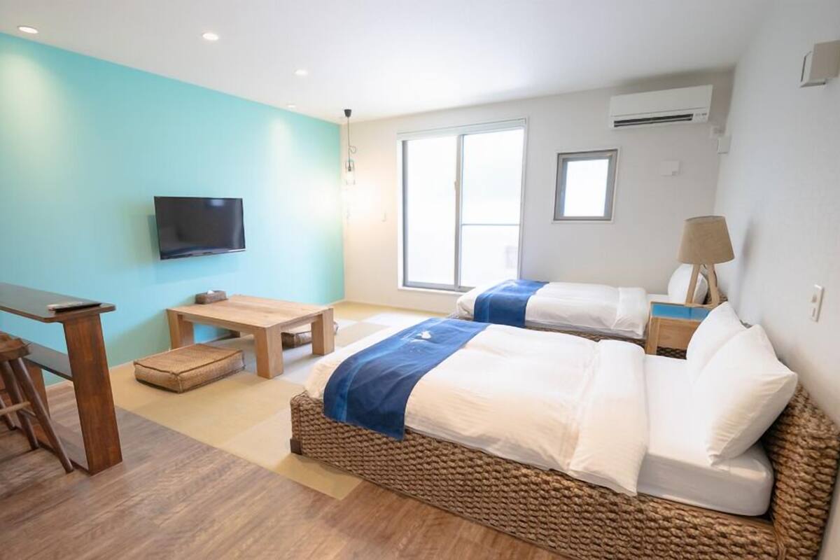 A hotel room with a bed, a desk, a TV, and a window.